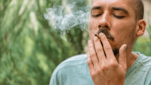 A man closes his eyes as he smokes a legal cannabis joint