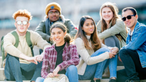 A group of smiling teens poses outdoors for a photo