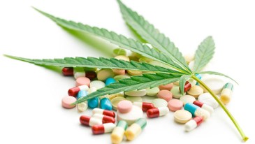 Marijuana leaf laid over pills