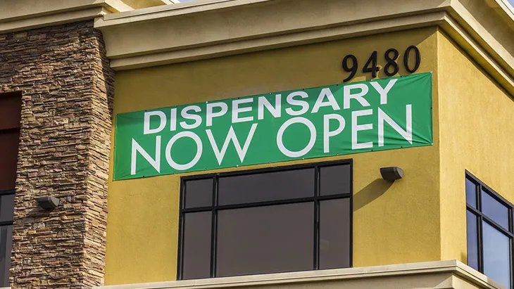 Banner reading "Dispensary now open" hangs on the exterior of a legal marijuana dispensary